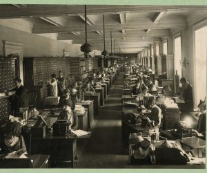 Photograph shows employees in the Library of Congress Copyright Office working at their desks and at the card catalog.